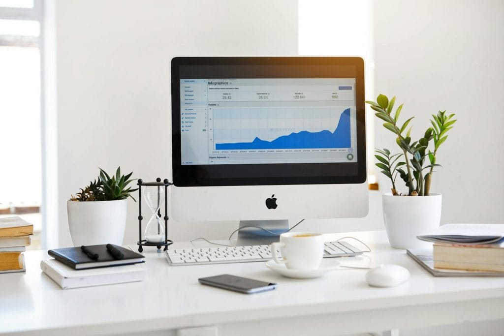 A clean, contemporary workspace featuring a desktop with analytics on the screen and plants for a fresh look